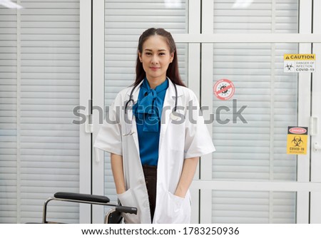 Close-up of an Asian woman in a hospital smiling and looking at the camera on a white background.