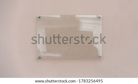 Transparent glass advertising signboard on concrete wall mock-up front view