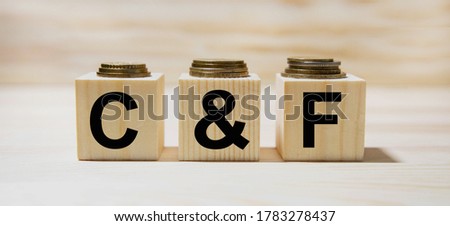 C and F the word on wooden cubes, cubes stand on a reflective surface, in the background is a business diagram. Business and finance concept