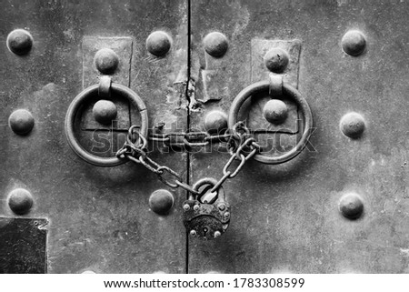 A lock and chain on a medieval door. Black and white photo. 