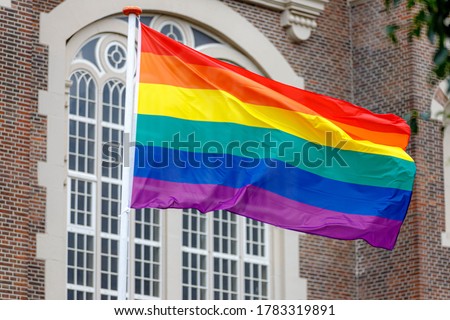 Celebration of Gay Pride in Amsterdam with rainbow flags hanging outside building along street, LGBT annual festival to celebrate that we can be who we are and love, Netherlands.