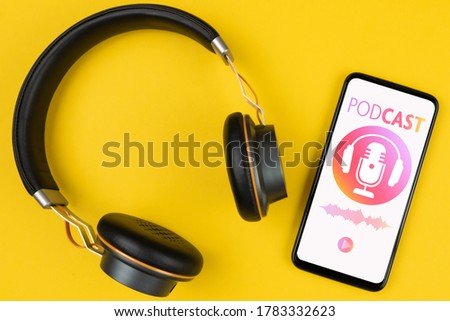 podcasting concept, above view of headphones and smartphone with podcast player mockup on yellow background