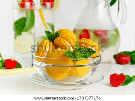 Yellow macaroons in a glass bowl on white background. French dessert concept