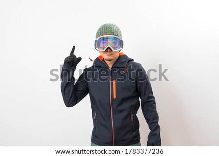 Asian man in a ski outfit ,gloves and goggles over white background.