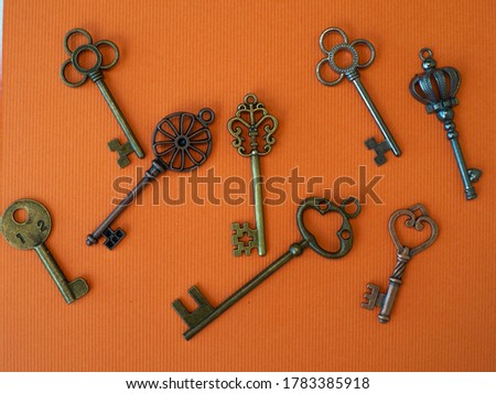 Many different old keys from different locks, scattered chaotically, flat lay. Finding the right key, encryption, concept. Retro vintage copper keys in bright orange background
