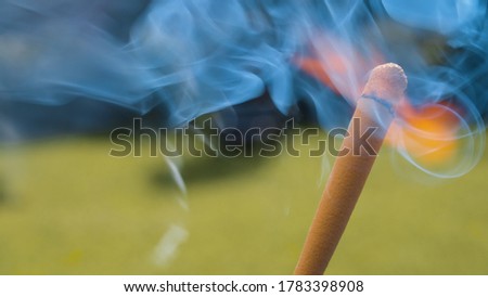 Extreme close up hunting match burning on natural background outdoors. The wind blows fire and smoke