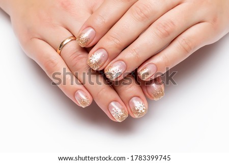 Winter manicure with painted snowflakes. Golden shiny manicure on square short nails close-up on a white background
