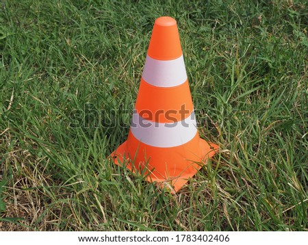 white and orange traffic cone in the grass