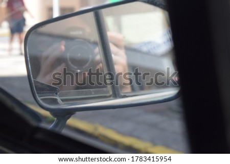Woman taking photograph with camera seen from the car rear view