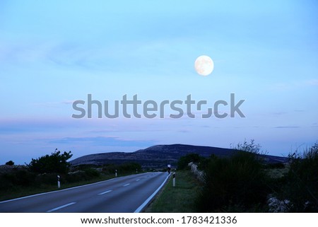 Atmospheric scene with full moon above road and rural landscape in the Croatian Island of Pag