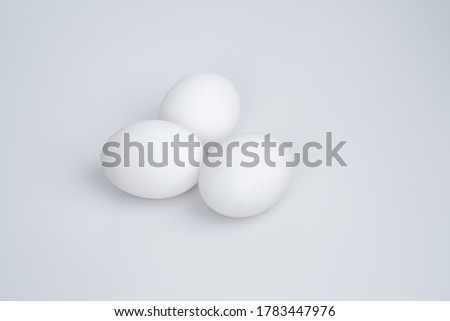 Three white eggs laying down on a white background