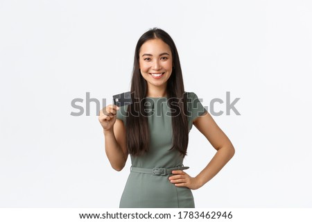 Small business owners, women entrepreneurs concept. Confident successful asian businesswoman in dress showing credit card, smiling pleased as making deposit, buying something
