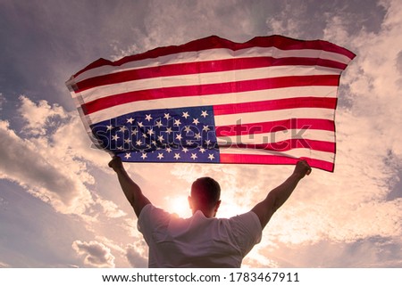 Man holding waving American USA flag in  hands during warm sunny evening in USA, concept picture