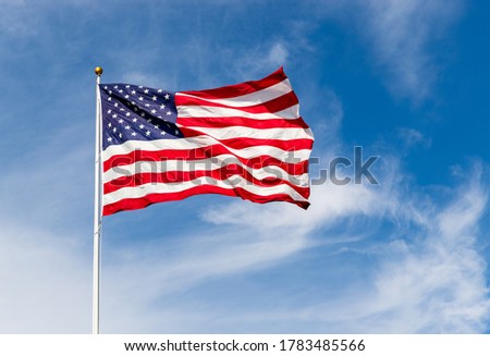 Beautiful American flag waving in the wind, with vibrant red white and blue colors against blue sky, with copy space. Royalty-Free Stock Photo #1783485566