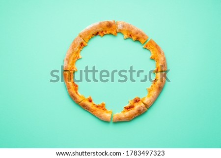 Flat lay with pizza pepperoni leftovers on a green-mint background. Pizza crust isolated on a colored background.