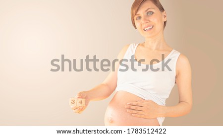 Pregnant young woman with pregnancy week number next to her belly. Photos of belly growth at 20 weeks pregnancy. Healthy pregnancy diet and fetal development.