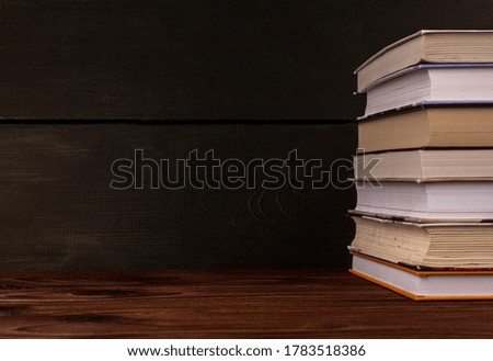 Close-up stack of books on a wooden table with space for text. Books in the library on the table. Literature about business. Novels and tales, adventures, stories. The background for design