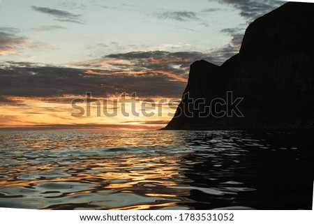 Beautiful sunset on the calm sea. Colorful sky and clouds. Amazing landscape in the norwegian fjord - view from the boat. Horizontal orientation photo.