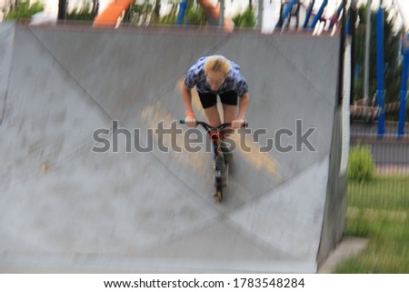 Motion blur photo effect. Young man with scooter making a jump on Skatepark during sunset