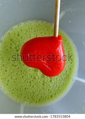 a red heart on the green juice in the glass