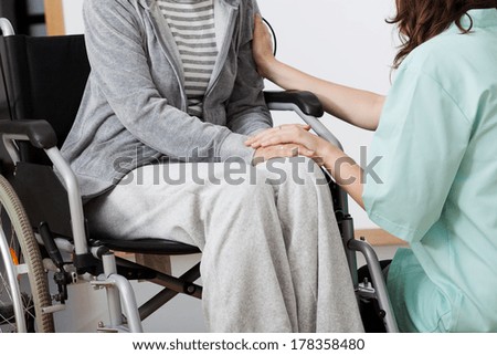 Nurse supporting elder lonely woman on wheelchair