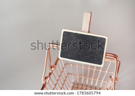 Black board with wooden details attached in the vintage supermarket basket. Clean surface. Price tag.  