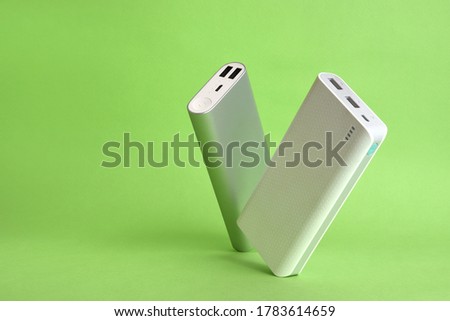 Two tilted power banks standing on a simple green background minimal Composition  Royalty-Free Stock Photo #1783614659