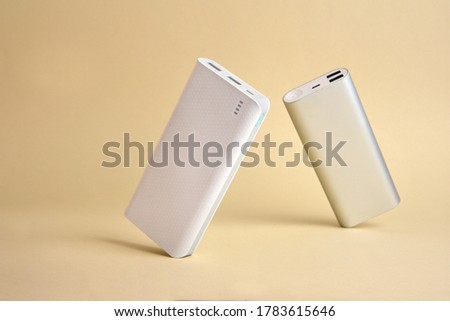 Two tilted power banks standing on a simple gold background minimal Royalty-Free Stock Photo #1783615646