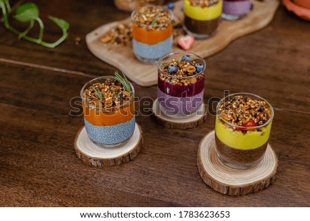 Colorful healthy breakfast sweet deserts few different chia puddings in glass jars on wooden table in kitchen at home.  