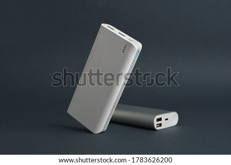 two white silver tilted power banks standing and sleeping on a simple black background minimal  Royalty-Free Stock Photo #1783626200