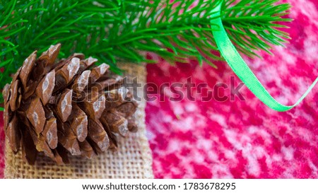 New Year and Christmas card. Christmas decorations on a red plaid. A spruce branch, a pine cone and a green satin ribbon lie on a winter blanket. Place for your text. Copy space. Selective focus.