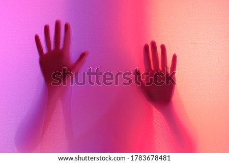silhouette of the women's palms photograph through a fabric with lighting of different colors. mysterious women