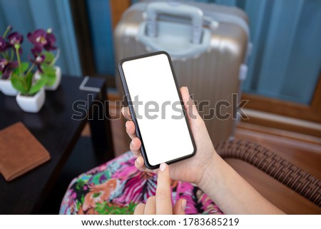 female hands holding phone with isolated screen and suitcase in an airport lounge