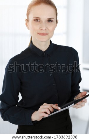 Business woman standing straight and looking at camera in white office. Business people concept
