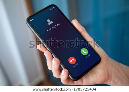 female hand holding phone with incoming call on the screen blue background Royalty-Free Stock Photo #1783725434