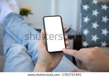male hands in jeans holding phone with isolated screen in room house