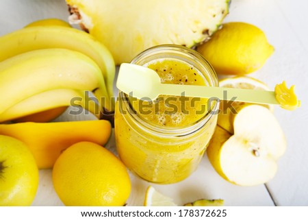 Fresh organic yellow smoothie with banana, apple, mango, pear, pineapple and lemon as healthy drink