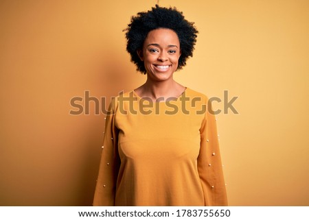 Young beautiful African American afro woman with curly hair wearing casual t-shirt with a happy and cool smile on face. Lucky person.
