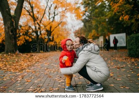 Picture of cheerful family of two. Beautiful caucasian mother cares for her little child in time their walking in the big park zone.