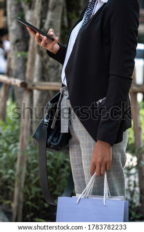 Unrecognizable business woman holding shopping bags and using phone stock photo