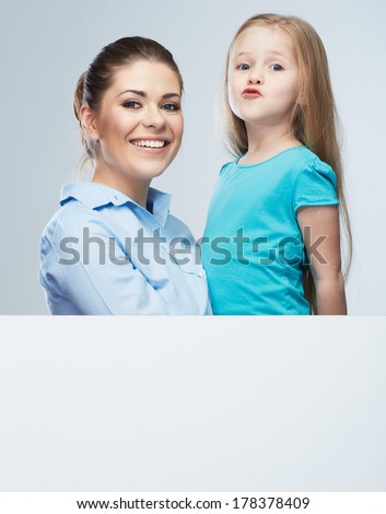 Business woman with kid girl isolated portrait behind white board. Mother and daughter embrace. Female model.