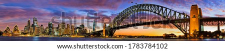 Wide panorama of city of Sydney waterfront on Harbour around Circular Quay, the Rocks and the Sydney harbour bridge at sunset.