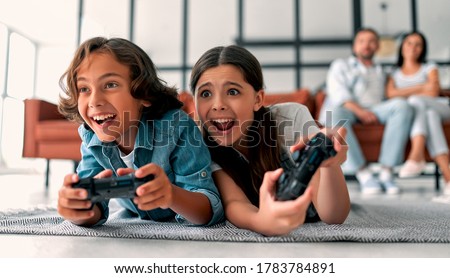 Beautiful mother and handsome father with their daughter and son spending time together at home. Children are playing video games. Happy family concept. Royalty-Free Stock Photo #1783784891