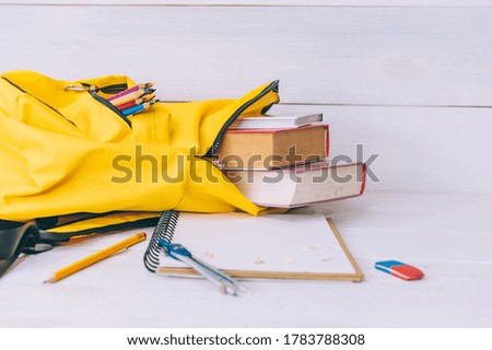 Back to school concept. Yellow with notepad and books on a wooden background