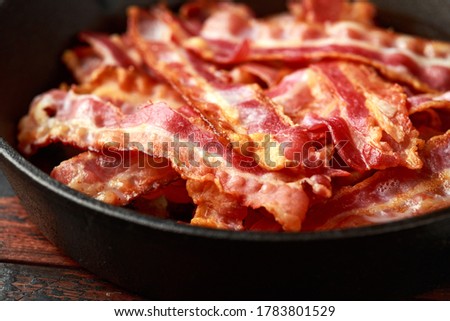 Fried crunchy Streaky Bacon pieces in a cast iron skillet Royalty-Free Stock Photo #1783801529