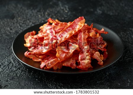 Fried crunchy Streaky Bacon pieces in a black plate Royalty-Free Stock Photo #1783801532