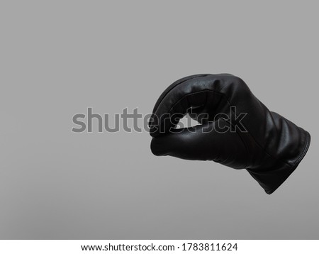 black leather glove showing pacman gesture. isolated neutral background. copy space