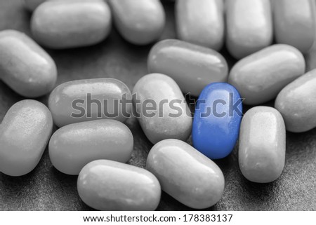 Color pill over many dark ones. Standing out from the crowd - concept image.  