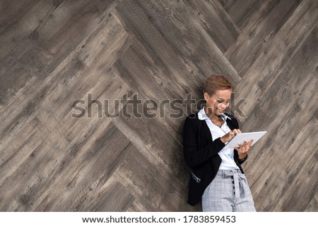 Business woman using digital tablet over brown wooden wall stock photo