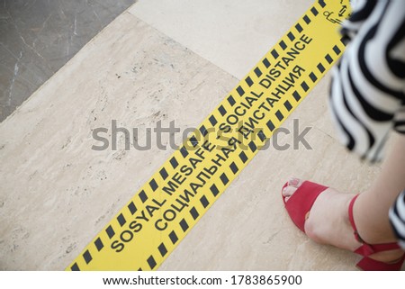Store or hotel markings on the floor, keep a social distance at least 1,5 meters. a woman stands near a marking on the floor,woman standing on a chekout counter with sign multi language	